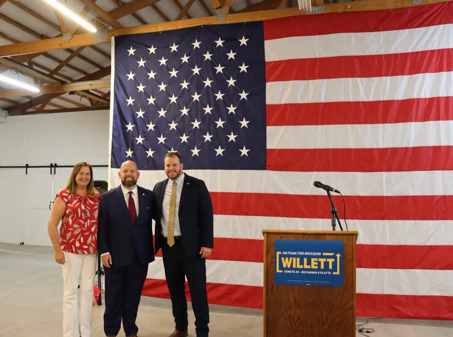 Chris Stigall, his wife, and Nathan Willett next to the Willett podium sign